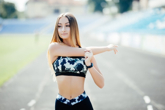 Portrait d'une femme de remise en forme faisant des exercices d'échauffement à l'extérieur