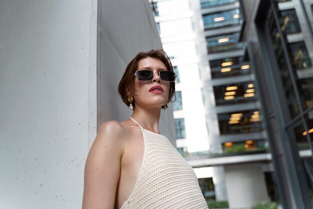 Photo gratuite portrait d'une femme riche à l'extérieur avec une robe élégante et des lunettes de soleil