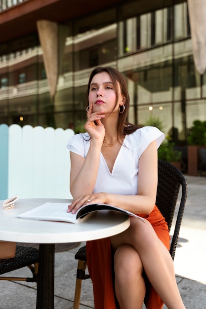 Photo gratuite portrait de femme riche lisant à l'extérieur