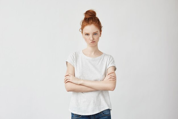 Portrait d'une femme rousse mécontente avec les bras croisés.