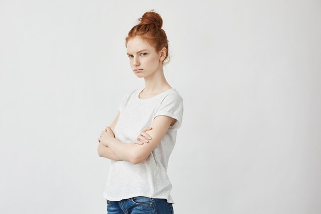 Portrait d'une femme rousse mécontente avec les bras croisés.