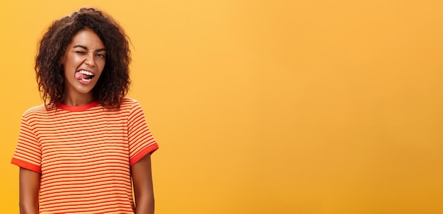 Photo gratuite portrait d'une femme séduisante et confiante, audacieuse et émotive avec une coiffure afro montrant joyeusement un clin d'œil