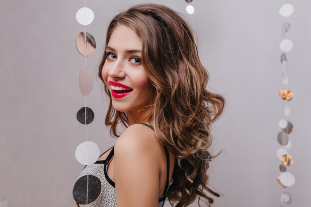 Portrait de femme séduisante avec des lèvres rouges de bonne humeur lors d'une fête avec des décorations en argent.