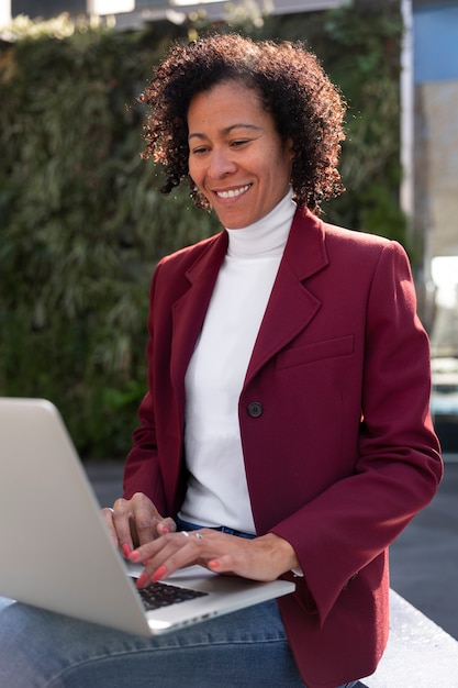 Portrait d'une femme senior en blazer professionnel à l'extérieur et d'un ordinateur portable