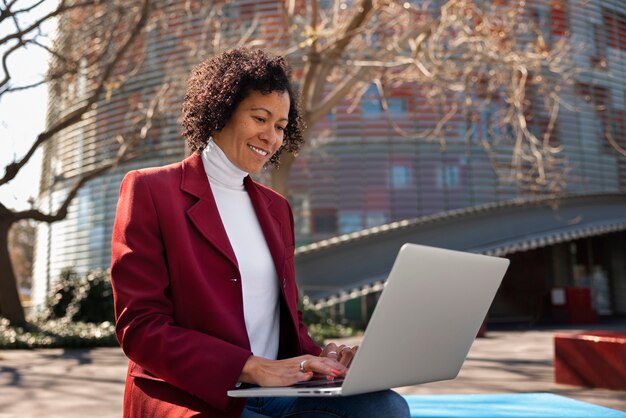 Portrait d'une femme senior en blazer professionnel à l'extérieur et d'un ordinateur portable