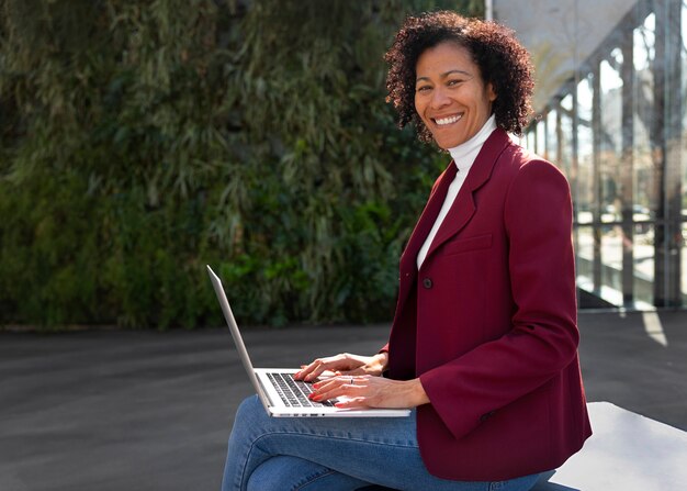 Portrait d'une femme senior en blazer professionnel à l'extérieur et d'un ordinateur portable