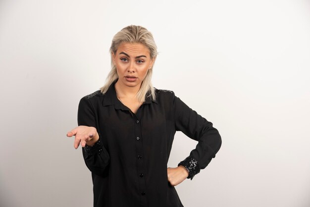 Portrait de femme sérieuse en chemise noire posant sur fond blanc. Photo de haute qualité