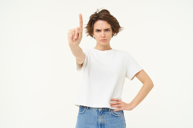 Photo gratuite portrait d'une femme sérieuse montre une règle d'un doigt ou un geste tabou désapprouve quelque chose de réprimande