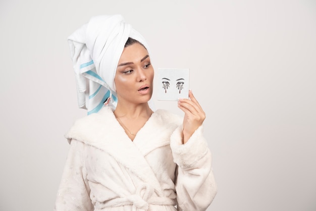 Portrait de femme en serviette blanche regardant la palette d'ombres à paupières