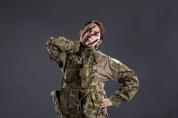 Portrait de femme soldat fatigué en camouflage sur mur sombre