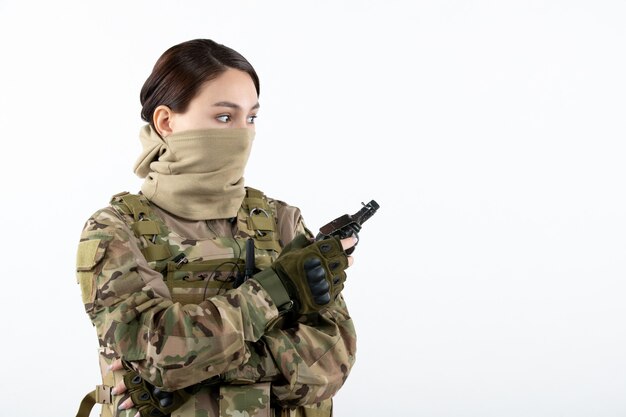 Portrait de femme soldat avec grenade en camouflage mur blanc