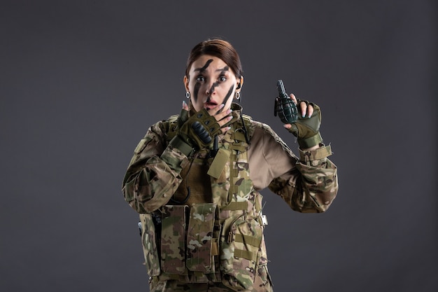 Portrait de femme soldat avec grenade dans ses mains sur mur sombre