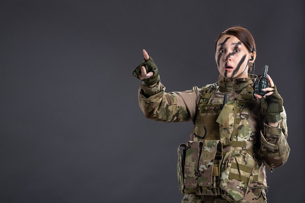 Portrait de femme soldat avec grenade dans ses mains sur mur sombre