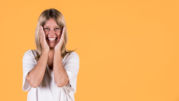 Portrait de femme sourde surprise, regardant la caméra sur fond jaune