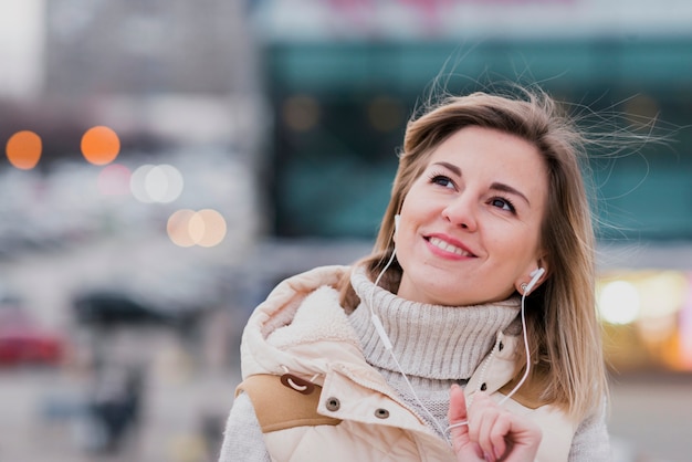 Portrait de femme souriante avec des écouteurs sur le toit