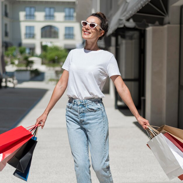 Portrait de femme souriante marchant avec des sacs à provisions