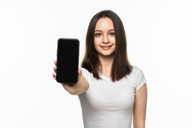 Portrait d'une femme souriante montrant un écran de smartphone vierge sur un blanc