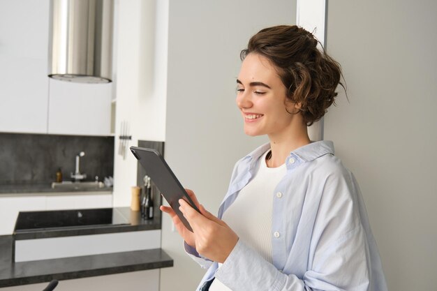 Portrait de femme souriante regardant sa tablette numérique lire un message en regardant des vidéos en ligne worki