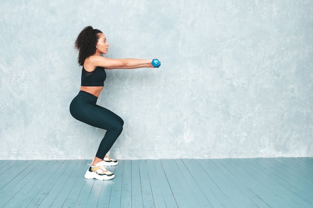 Portrait de femme souriante de remise en forme en vêtements de sport avec une coiffure afro curls