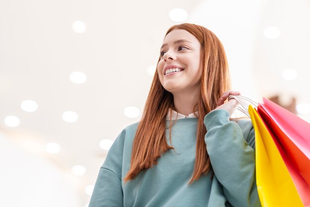 Portrait de femme souriante tenant des sacs en papier