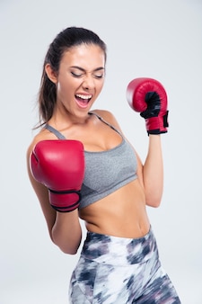 Portrait d'une femme sportive de succès avec des gants de boxe célébrant sa victoire isolée sur un backgorund blanc