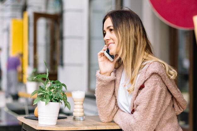 Portrait de femme de style jeune est assis dans la cafétéria dans la rue