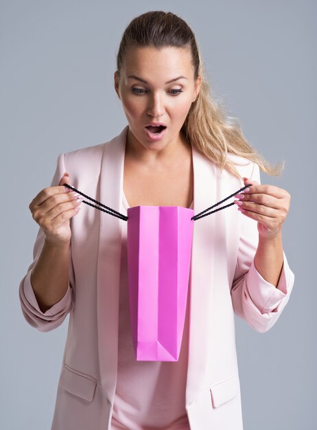 Portrait d'une femme surprise souriante heureuse avec sac à provisions rose.