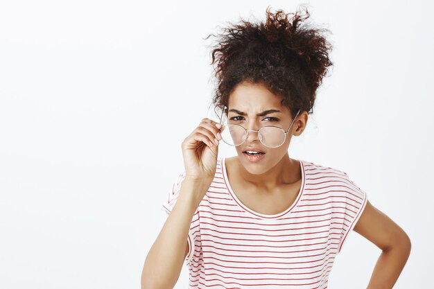 Portrait de femme suspecte avec une coiffure afro qui pose en studio