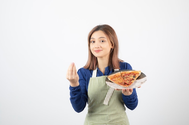 Portrait de femme en tablier de cuisine montrant une assiette de pizza sur blanc