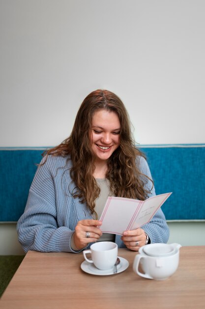 Portrait d'une femme de taille plus en train de boire un verre dans un restaurant