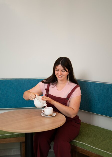 Portrait d'une femme de taille plus en train de boire un verre dans un restaurant