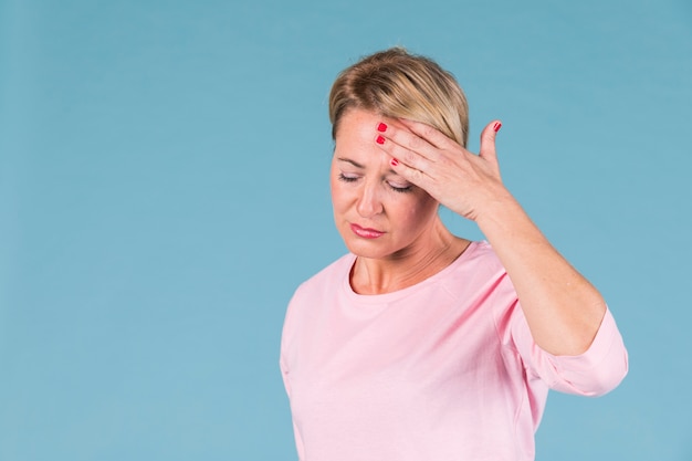 Portrait de femme tenant sa tête dans la douleur sur fond bleu