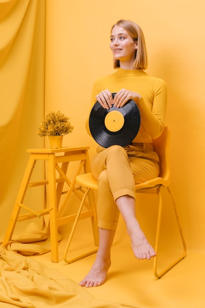 Portrait de femme tenant un vinyle dans une scène jaune
