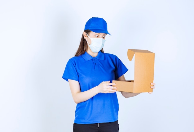 Portrait De Femme En Uniforme Et Masque Médical Ouvrant La Boîte De Papier