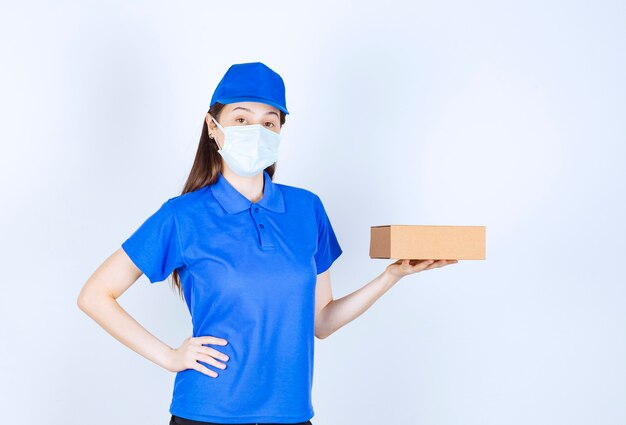 Portrait de femme en uniforme et masque médical tenant une boîte en papier