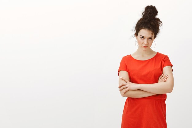 Portrait de femme urbaine attrayante douteuse aux cheveux bouclés peignés en chignon