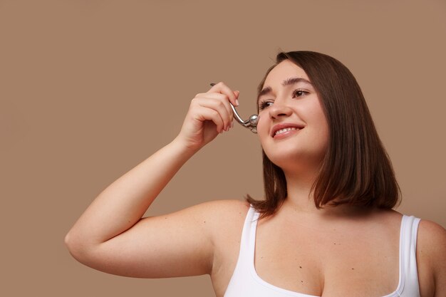 Portrait de femme utilisant un rouleau facial pour la beauté