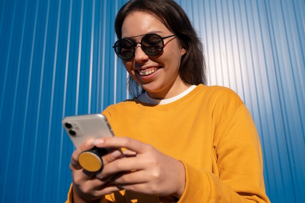 Portrait de femme utilisant un smartphone avec prise pop à l'extérieur