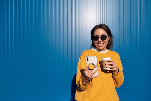 Photo gratuite portrait de femme utilisant un smartphone avec prise pop à l'extérieur