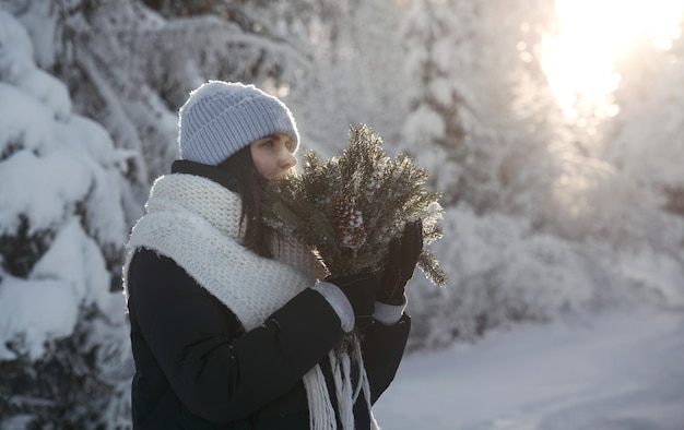 Portrait D'une Femme En Vêtements D'hiver Tenant Un Bouquet De Branches De Pin Photo Premium