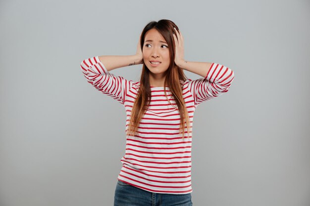 Portrait d'une fille asiatique perplexe, debout avec les mains