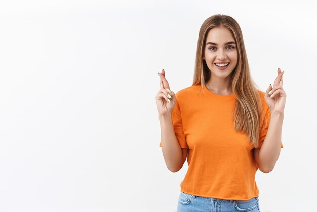 Portrait d'une fille blonde souriante confiante et optimiste espère que le souhait se réalisera, croisez les doigts bonne chance