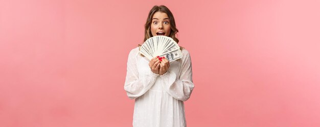 Portrait d'une fille chanceuse excitée aux cheveux blonds robe blanche gagner de l'argent recevoir un prix en espèces big lott