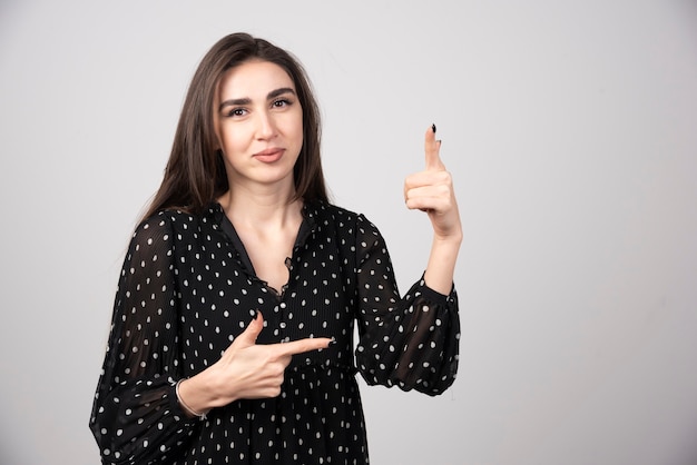 Portrait d'une fille charmante et élégante aux cheveux longs pointant de côté vers le haut.