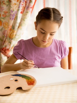 Portrait de fille concentrée dessinant sur toile par des peintures à l'huile
