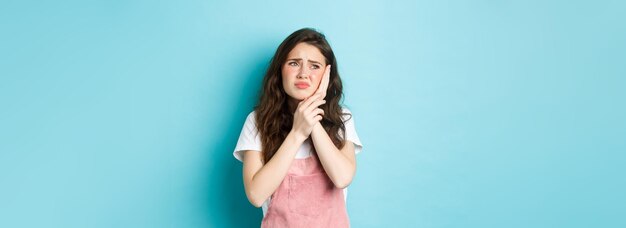 Portrait d'une fille fronçant les sourcils touchant la joue ayant mal aux dents regardant la stomatologie du coin supérieur gauche c