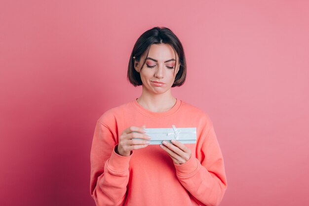 Portrait de fille frustrée bouleversée ouverture boîte-cadeau isolé sur fond rose