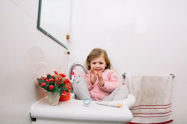 Portrait d&#39;une fille heureuse assis dans le lavabo de la salle de bain