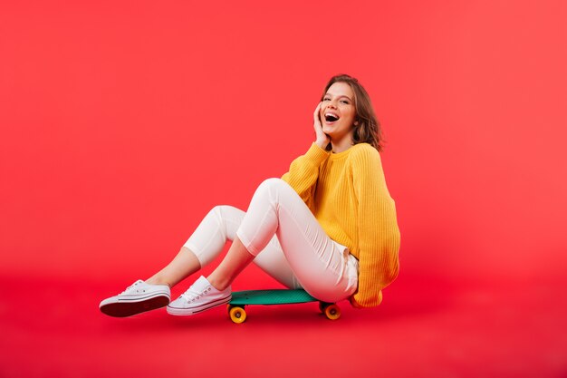 Portrait d'une fille heureuse assise sur une planche à roulettes