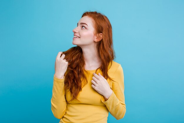Portrait d&#39;une fille heureuse de gingembre avec des taches de rousse en regardant la caméra. Fond bleu pastel. Espace de copie.